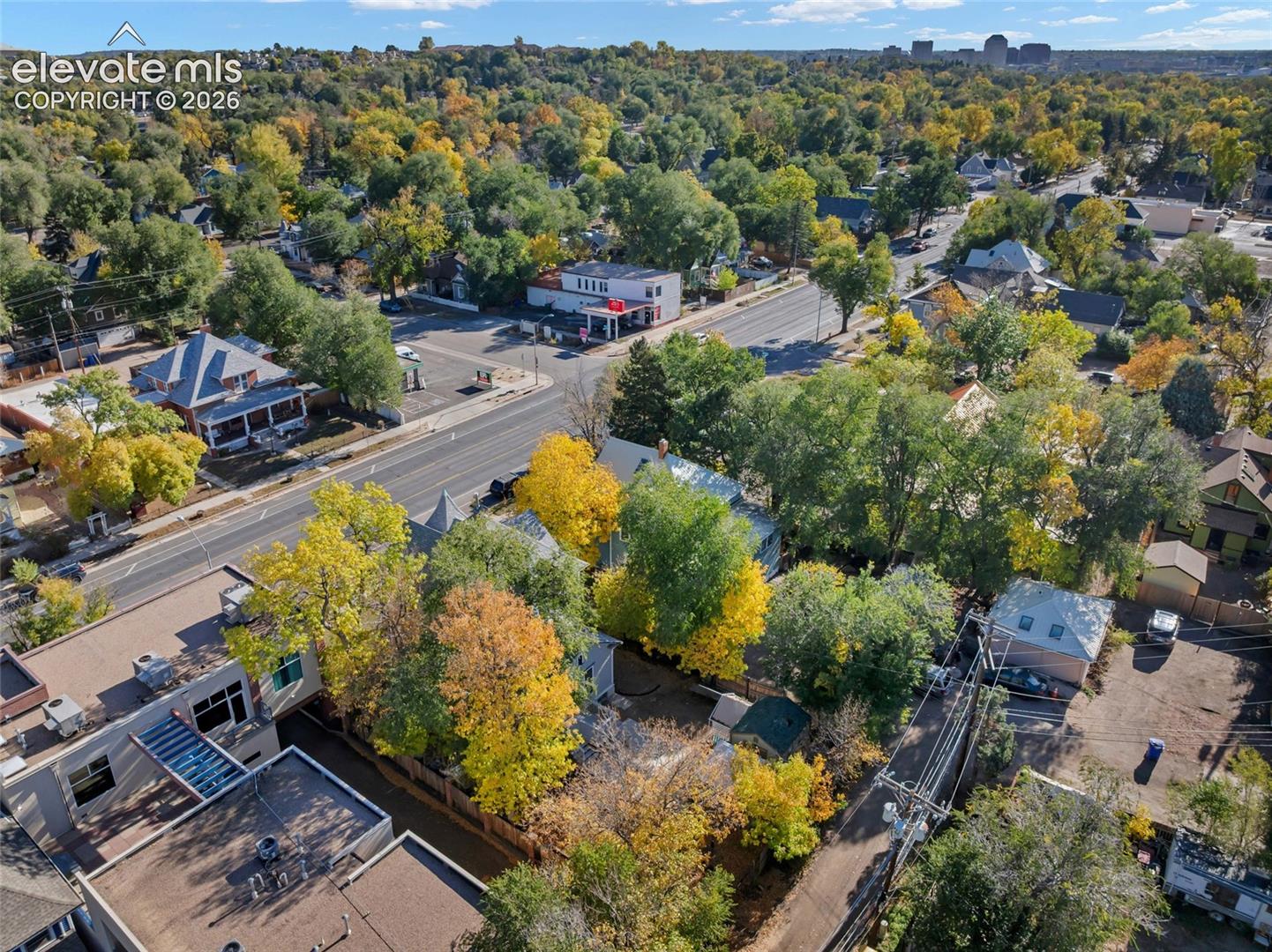 Aerial perspective featuring mature deciduous trees, landscaped grounds, and proximity to city infrastructure