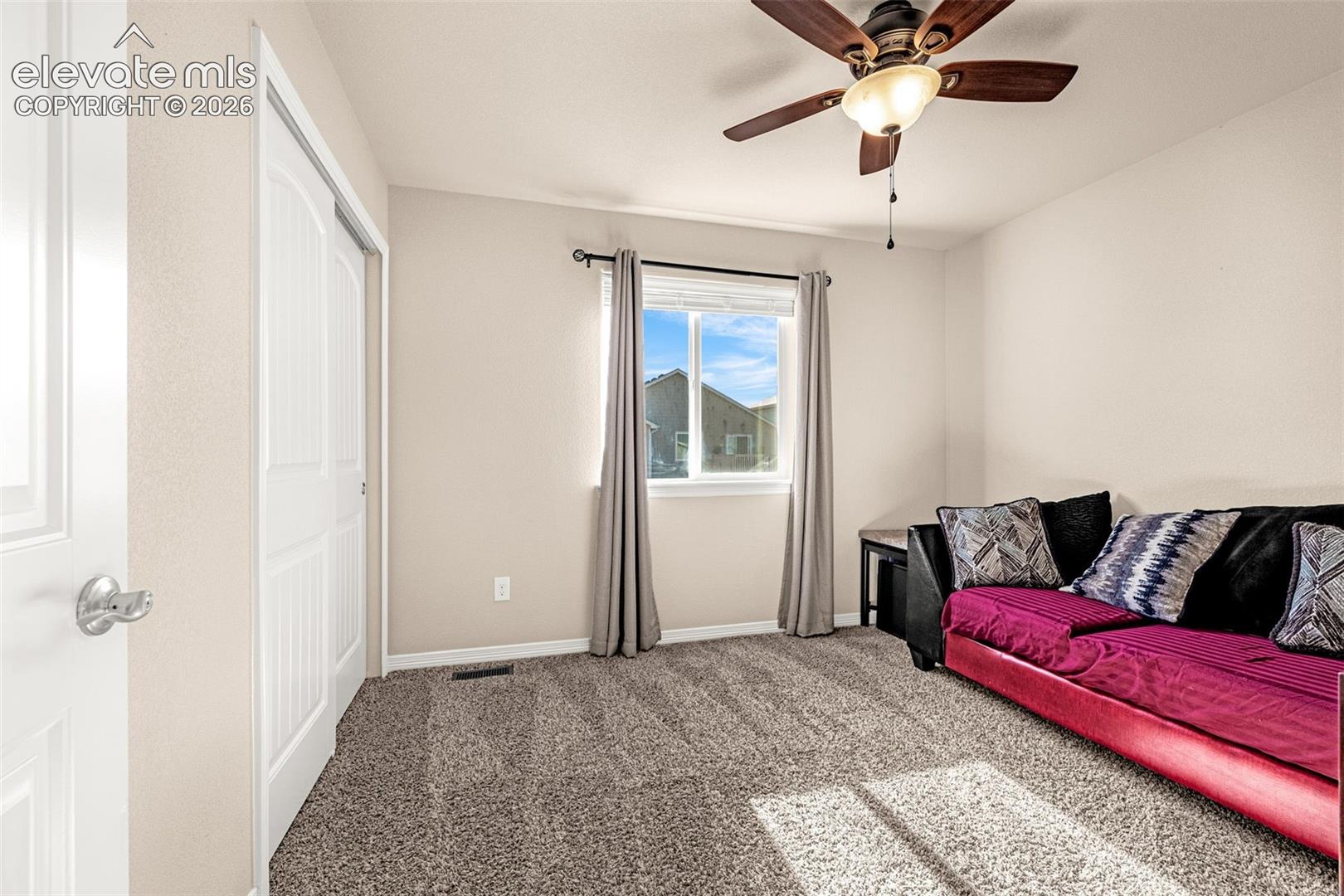 Neutral wall paint, carpet flooring, a ceiling fan with integrated lighting, a double-door closet, and a window with blinds