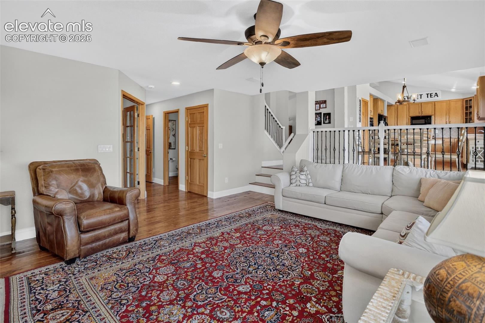Open living area with wood-finish flooring and a ceiling fan