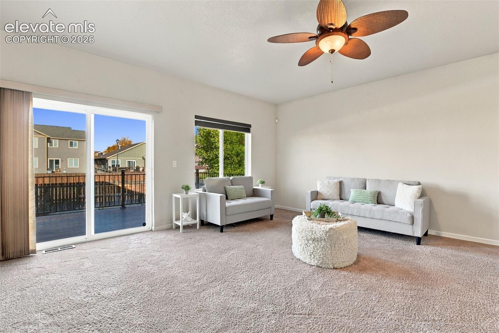 High ceilings featuring a palm-leaf blade ceiling fan, wall-to-wall carpeting, and sliding glass doors providing outdoor access