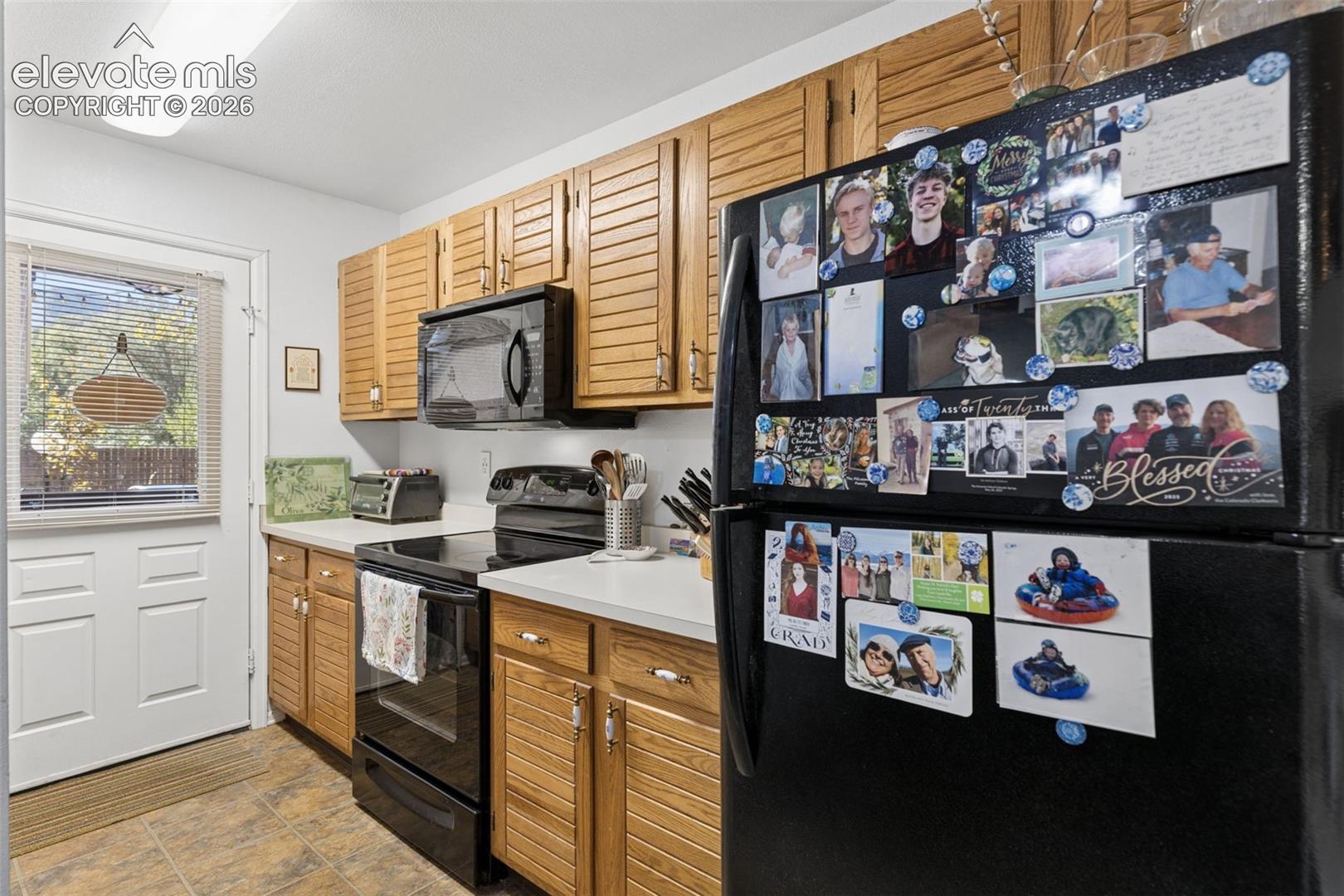 Wood cabinetry with louvered doors, white countertops, built-in microwave, and electric range