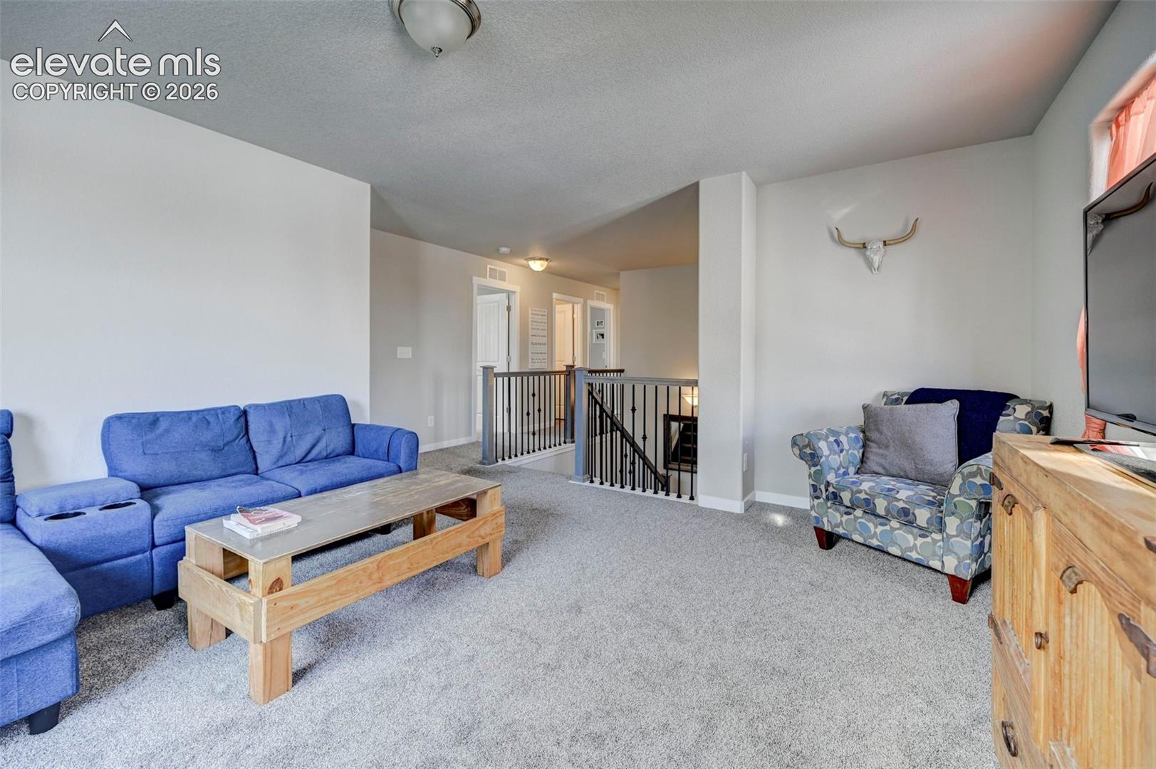 Interior space featuring neutral wall tones, wall-to-wall carpeting, and a staircase landing with metal railings and balusters