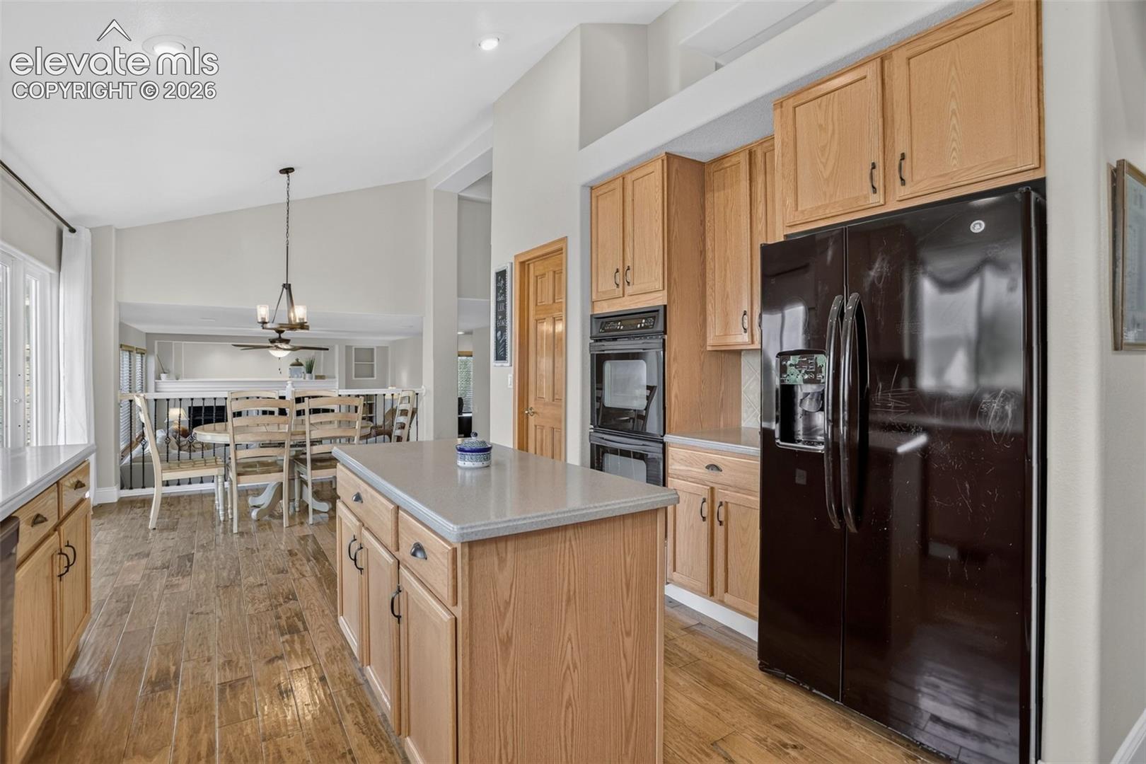 Kitchen featuring wood-finish flooring, a central island with countertop, natural wood cabinetry, and a double wall oven