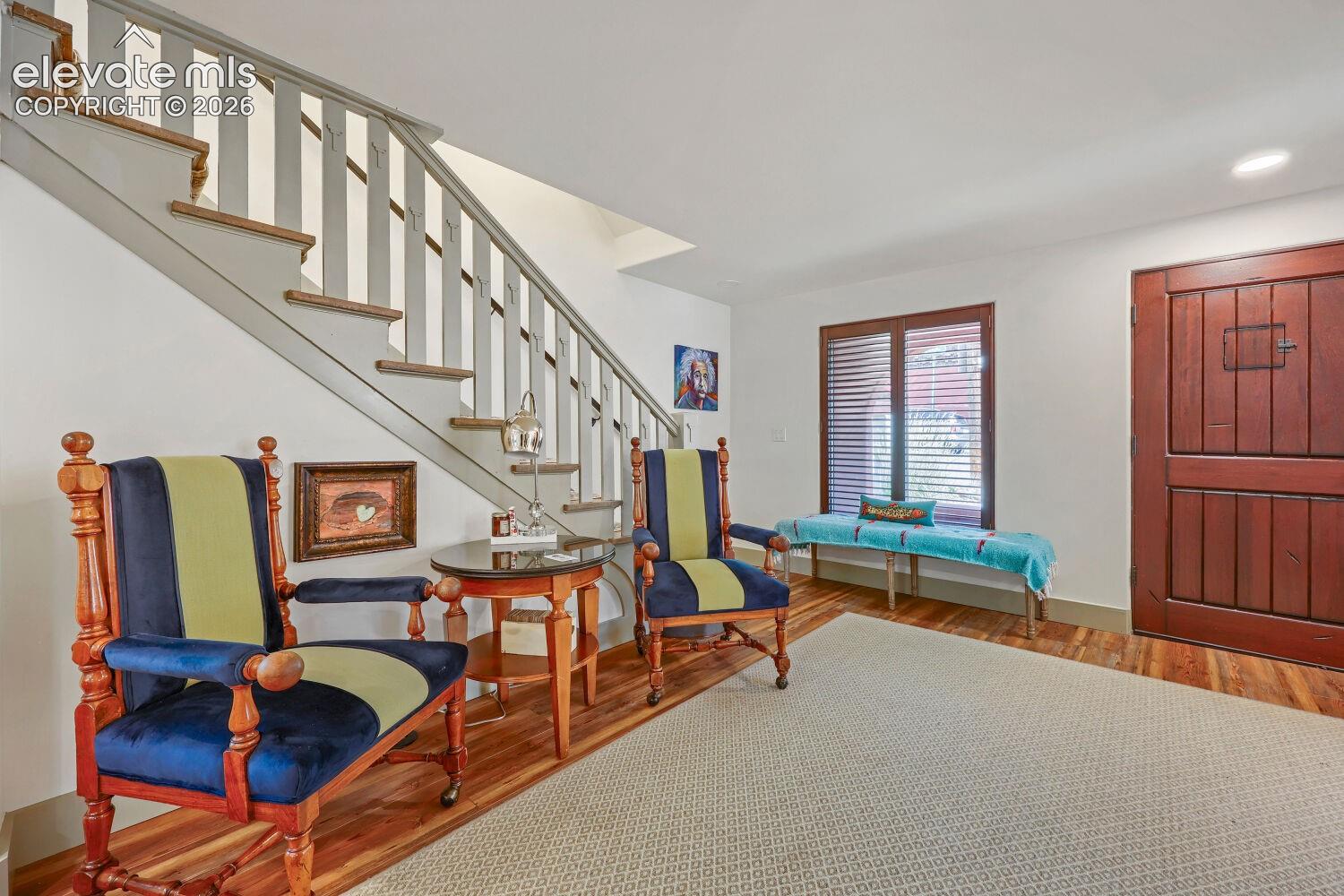 Wood-finish flooring, staircase with painted risers and wood treads, built-in recessed lighting, and a wood-paneled door