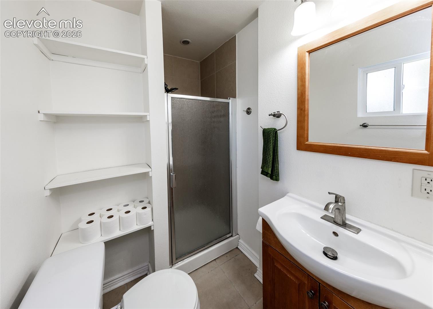 White vanity with a single basin sink, brushed nickel faucet, and a wood-framed mirror