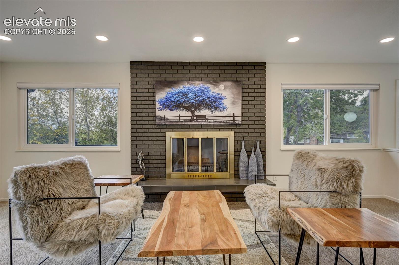 Floor-to-ceiling dark brick fireplace feature with a metal screen and stone hearth, flanked by dual slider windows with recessed lighting above