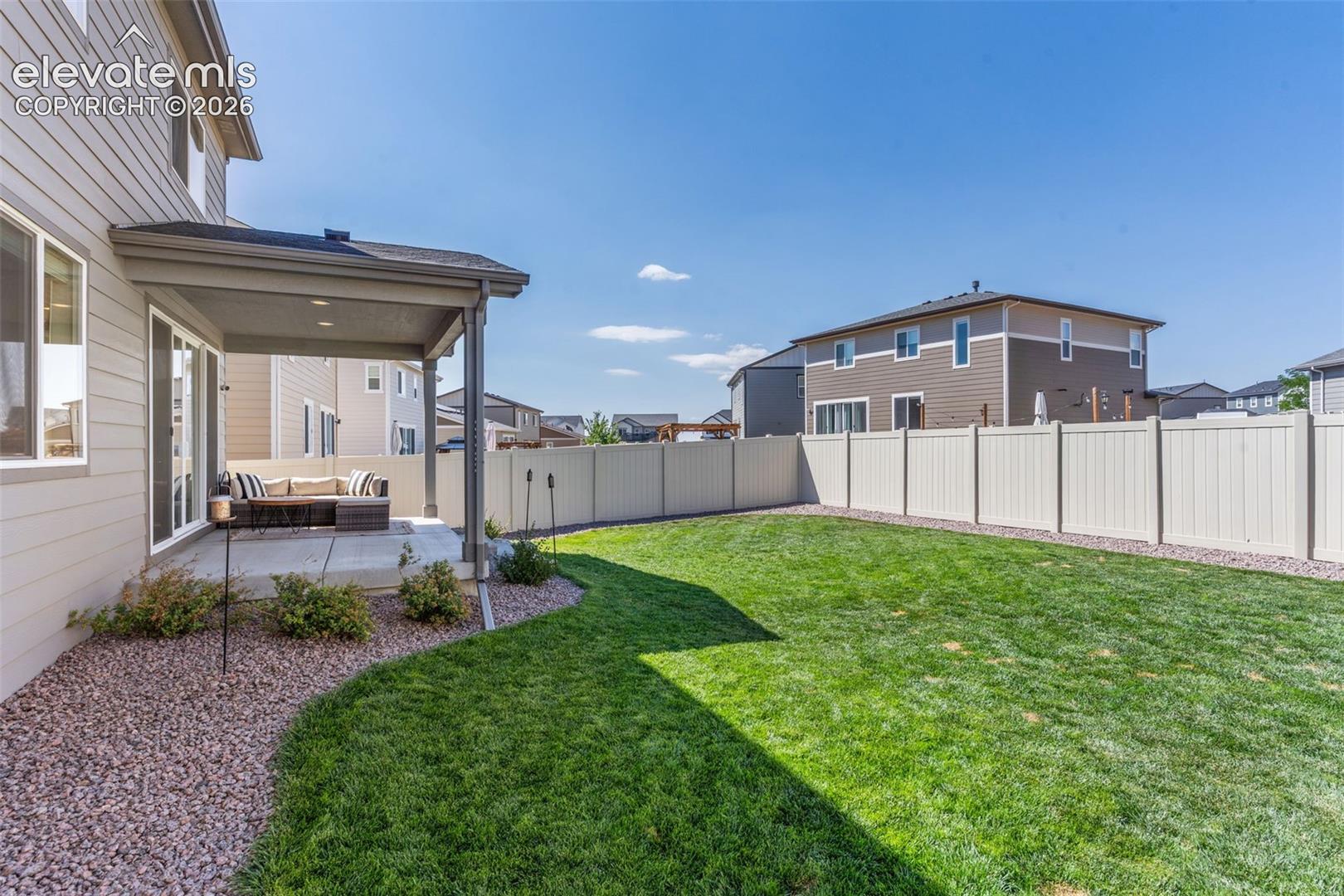 Expansive green lawn with a covered concrete patio