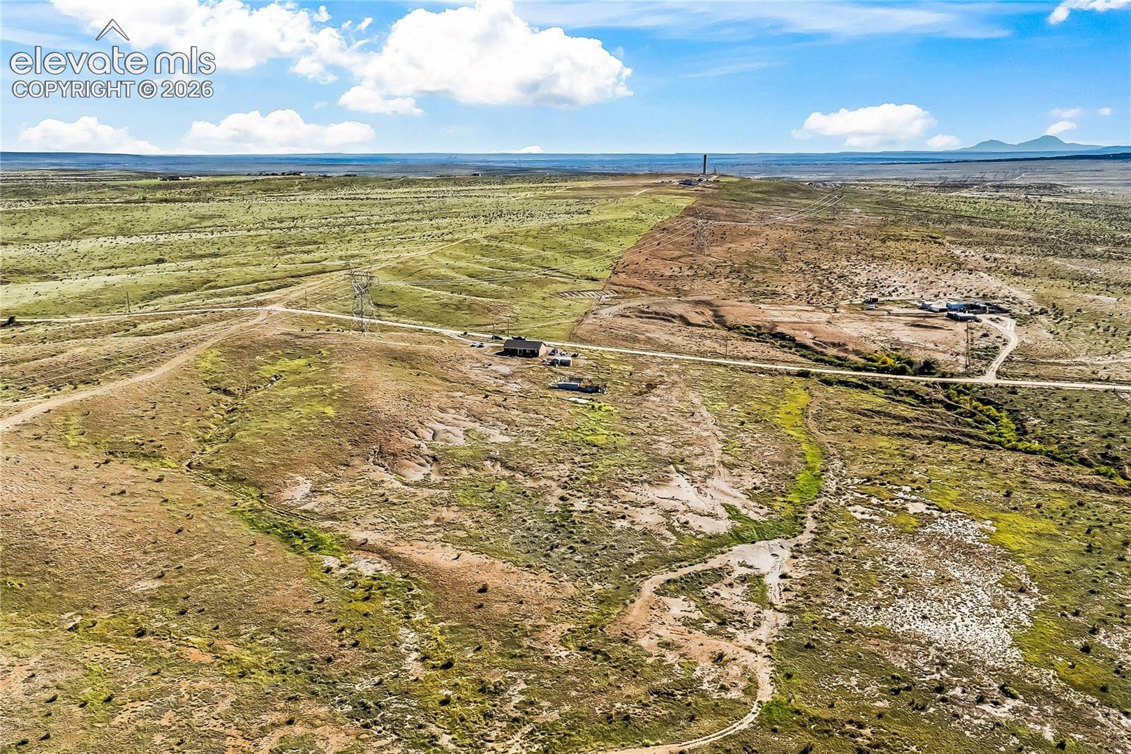 Expansive acreage featuring rugged desert terrain, unpaved road access, and prominent mountain horizon