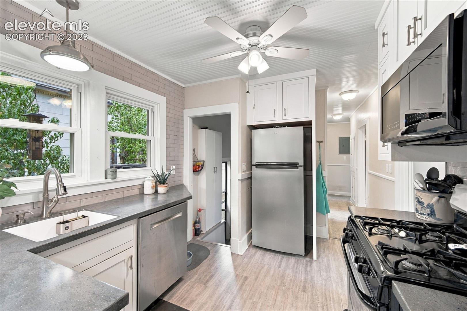 Kitchen featuring white cabinetry, wood-finish flooring, beadboard ceiling, stainless steel appliances, and solid surface countertops