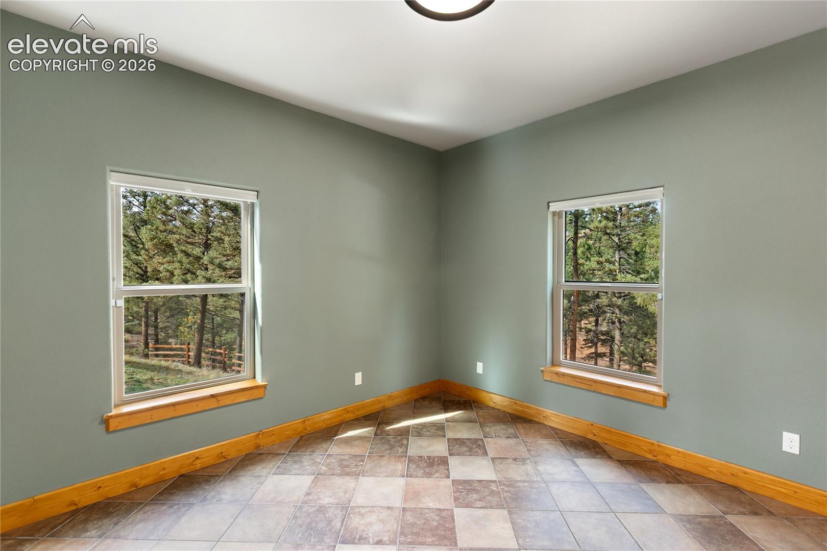 Room featuring dual-aspect windows, natural wood-finish window sills, tile flooring, and neutral wall tones