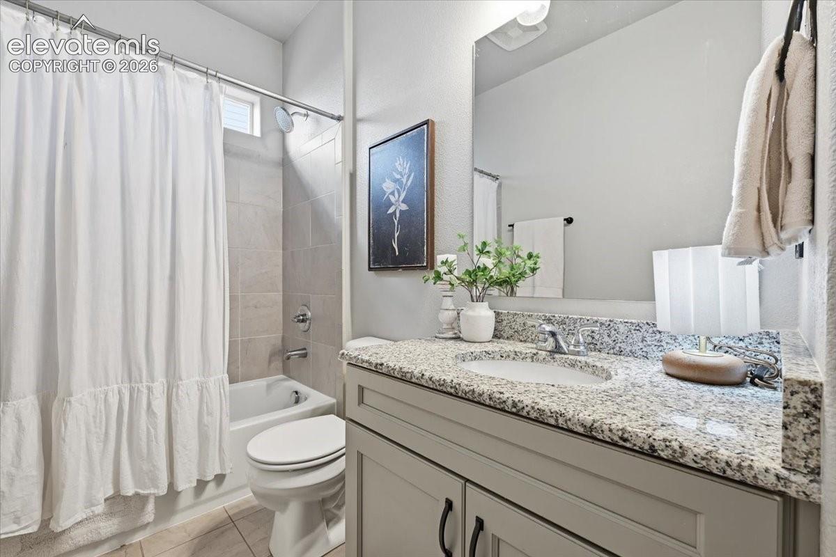 Bathroom with a bathtub, shower combination with tile surround, a single vanity with stone countertop, and an undermount sink