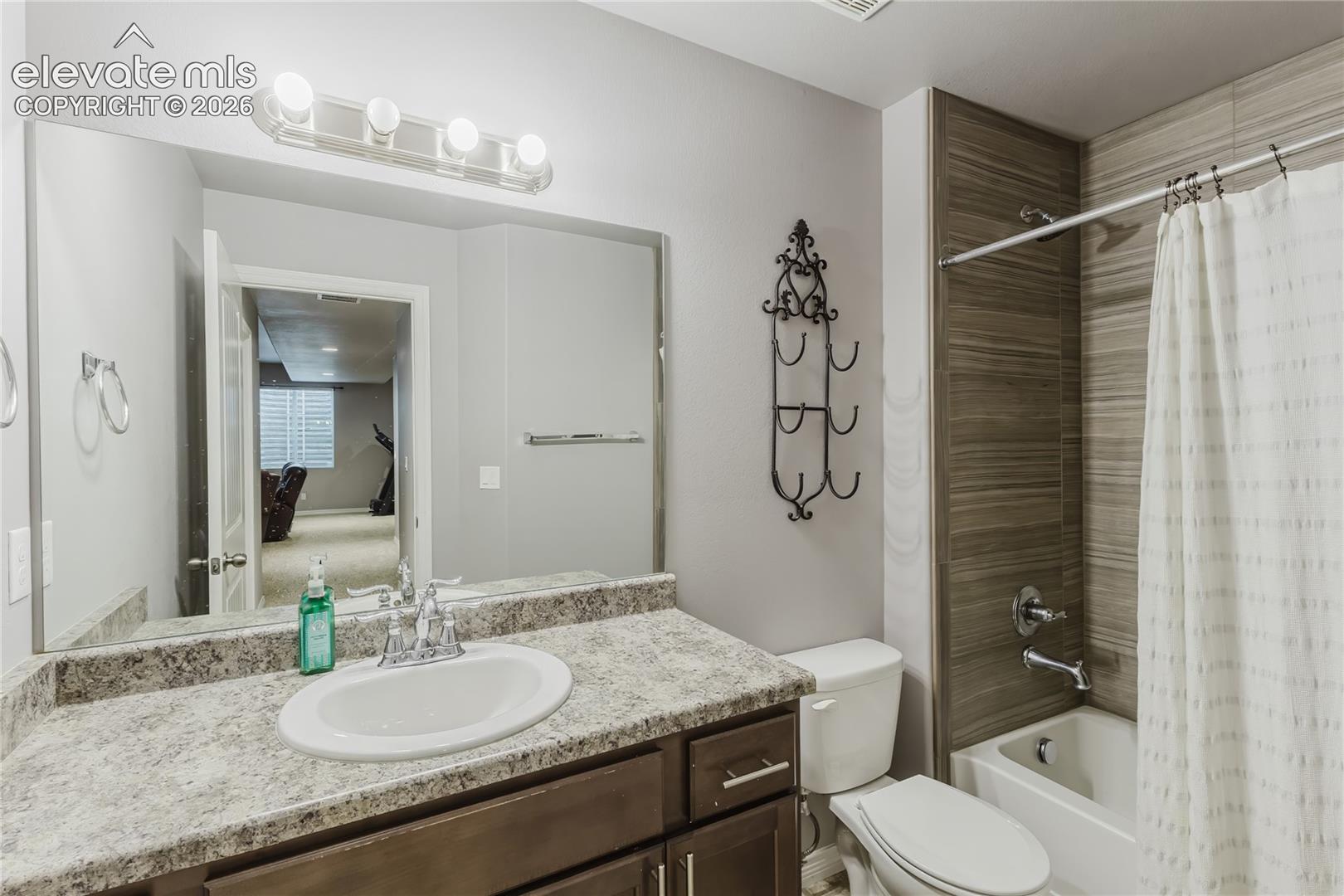 Bathroom featuring a single vanity with a laminate countertop, undermount sink, and chrome faucet