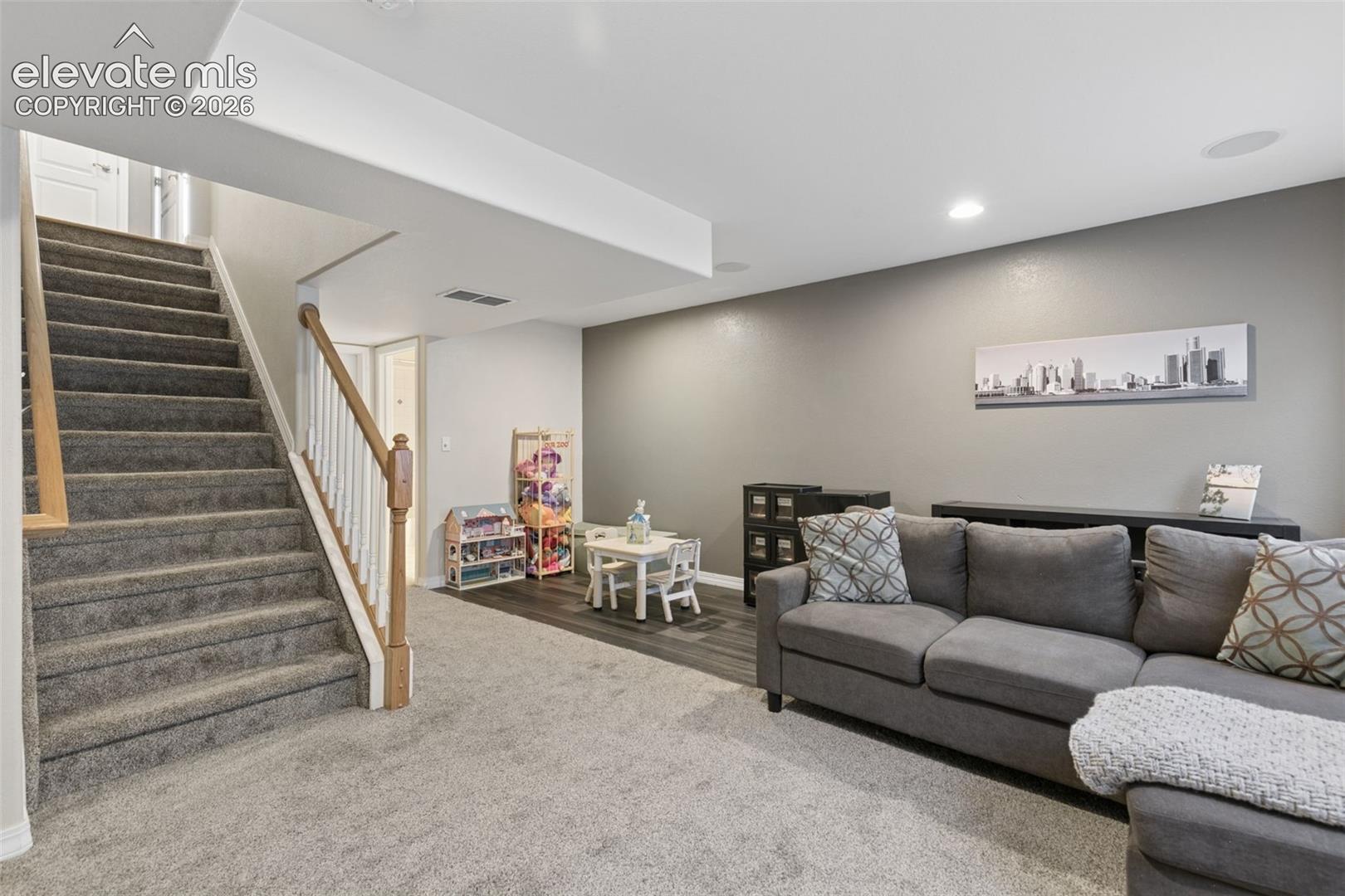 Carpeted staircase with wood railing, recessed lighting, and wood-finish flooring