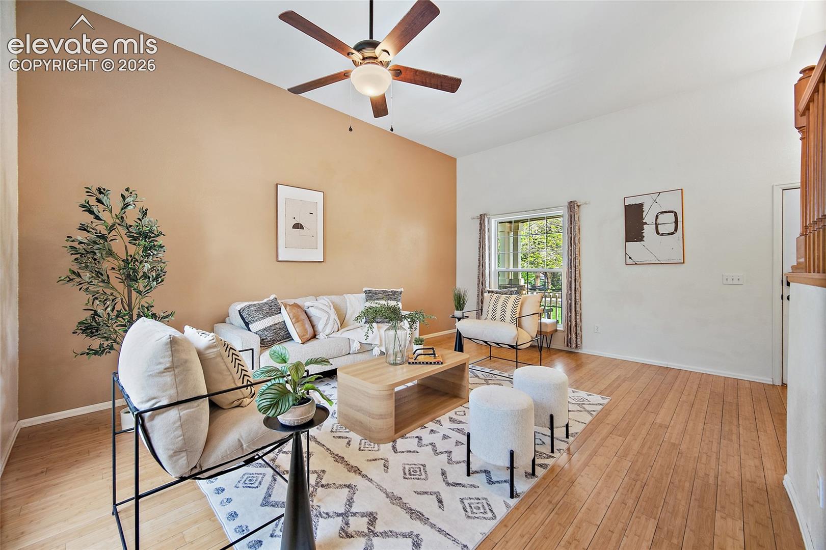 Living area featuring wood-finish flooring, a vaulted ceiling, and a ceiling fan