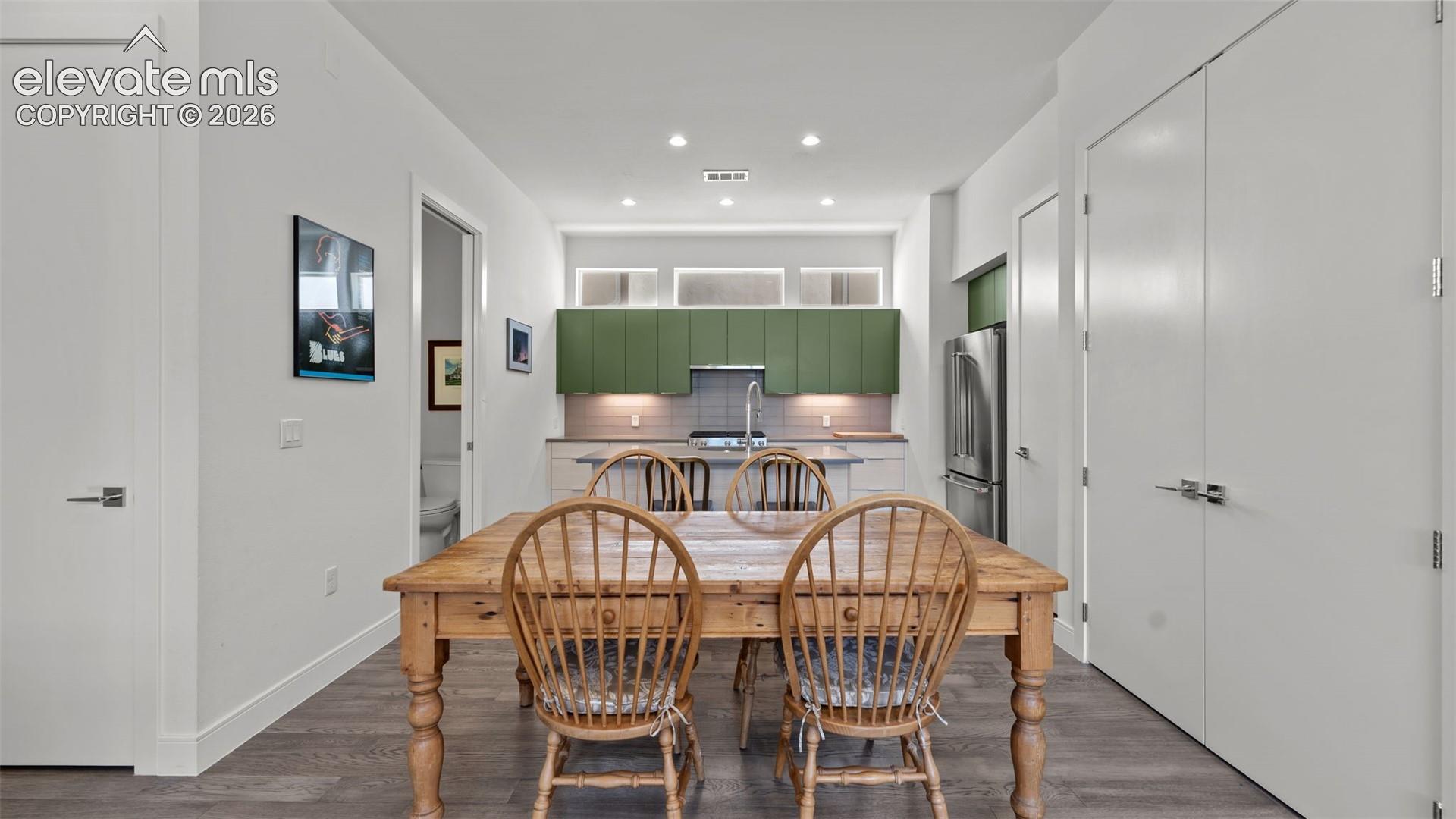 Kitchen featuring green cabinetry, tile backsplash, stainless steel refrigerator, stone countertops, and clerestory windows