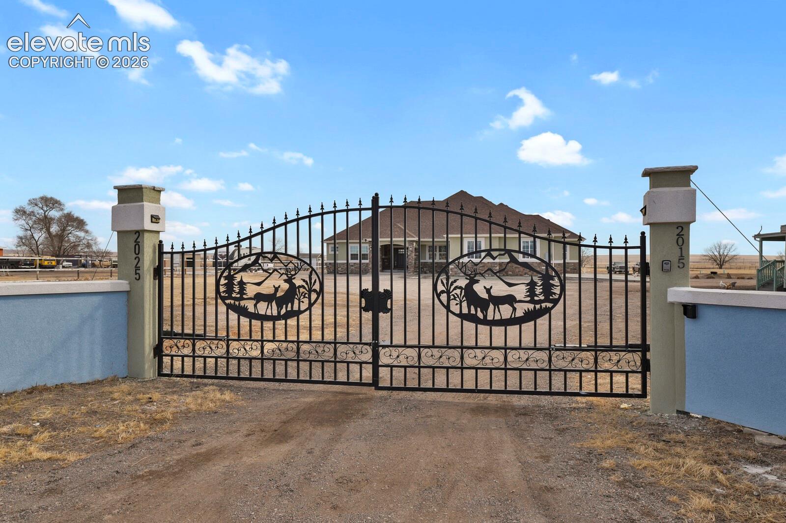 Custom wrought iron gate featuring decorative wildlife silhouettes and dual stucco-finished masonry pillars