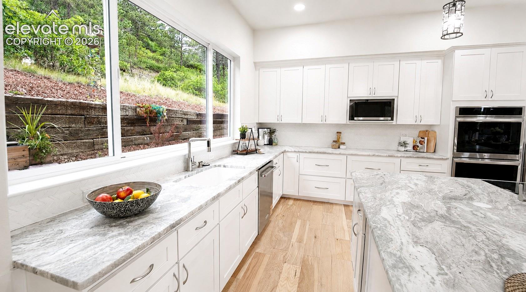 Light and bright Gourmet Kitchen with wall of windows, white cabinetry and leathered granite countertops.