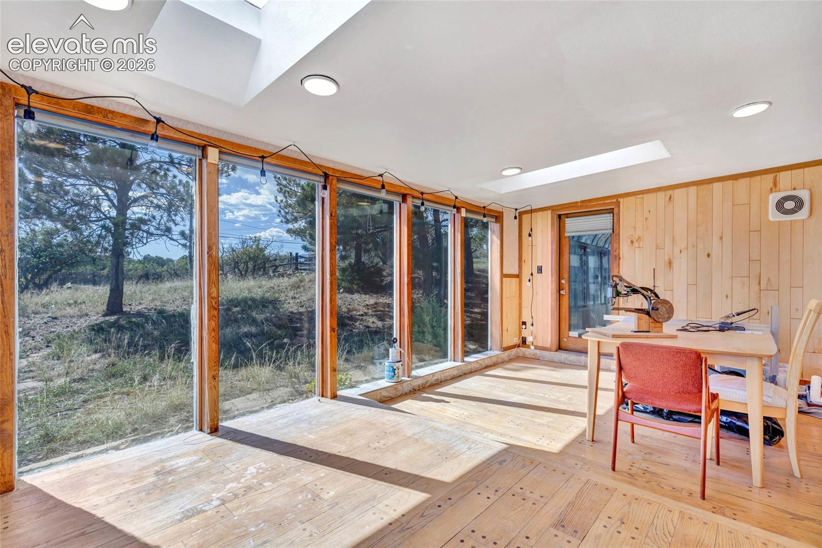 Expansive wall of windows with wood frames, wood-finish flooring, wood-paneled wall, and recessed ceiling lighting