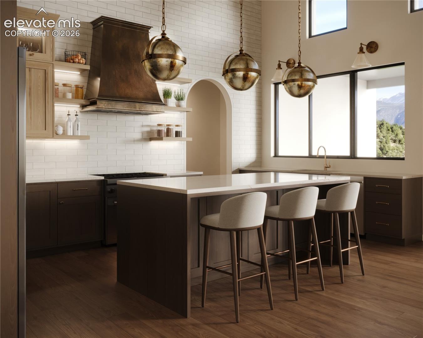 Hardwood-finish flooring, white subway tile backsplash, oversized kitchen island with light-toned countertop, built-in range, and custom range hood