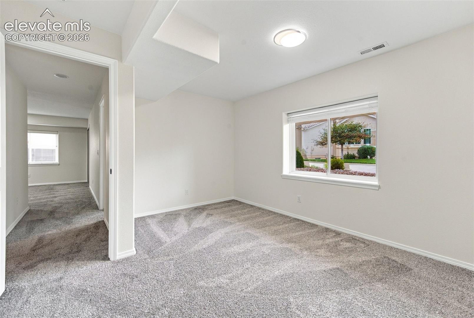 Neutral interior space featuring wall-to-wall carpeting, crisp white wall finish, and a large horizontal sliding window with white trim