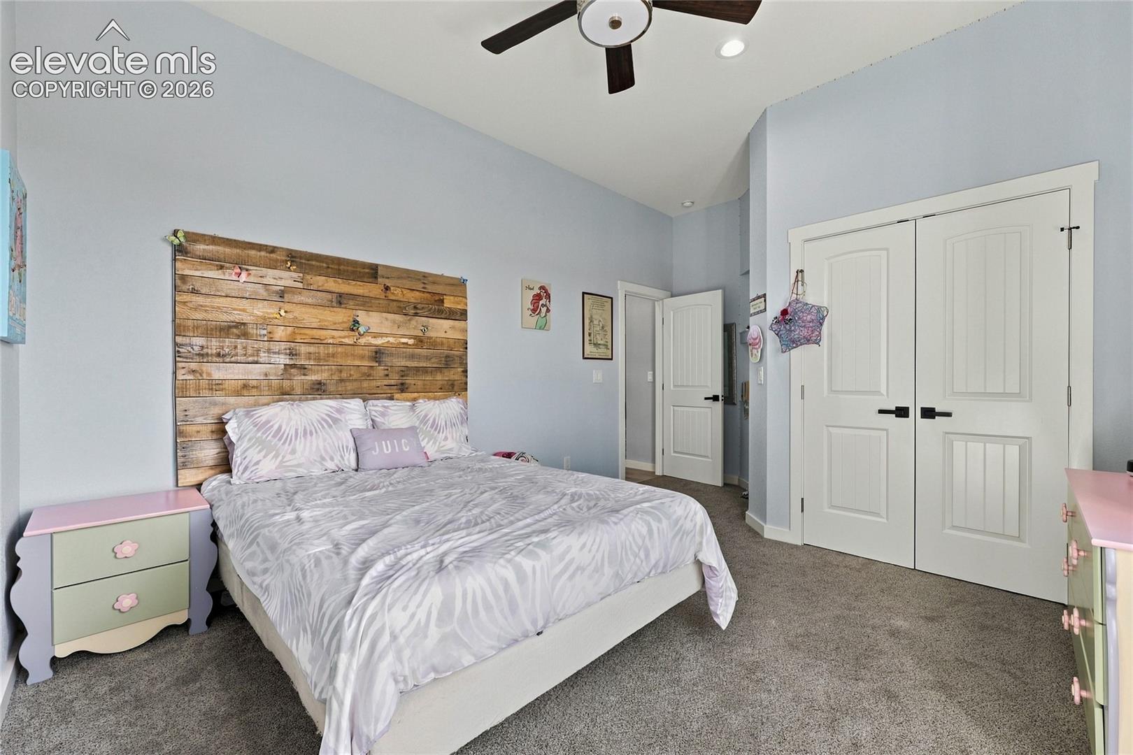 High ceilings with a ceiling fan, plank-style wood wall accent, and double-door closet with matte black hardware