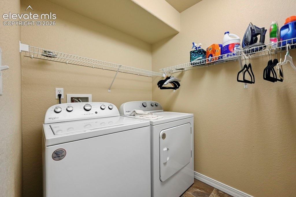 Basement laundry area featuring permanent shelving, a washer, and a dryer