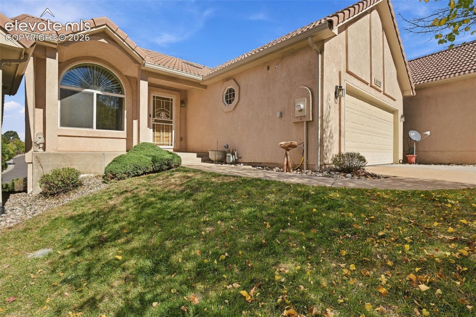 Stucco exterior featuring a tiled roof, arched window, decorative octagonal window, and an attached two-car garage
