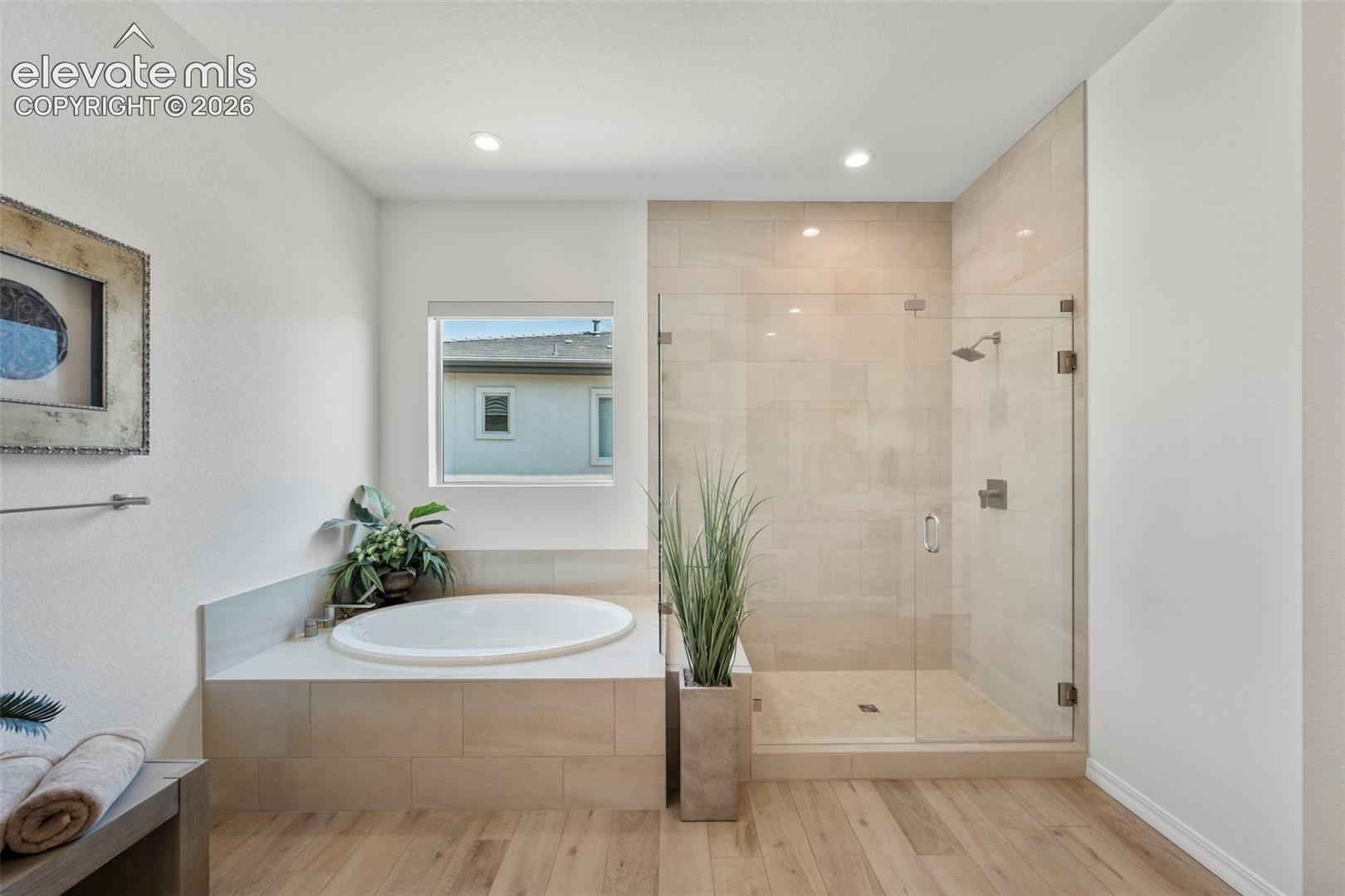 Recessed lighting illuminates the soaking tub and walk-in shower with clear glass enclosure