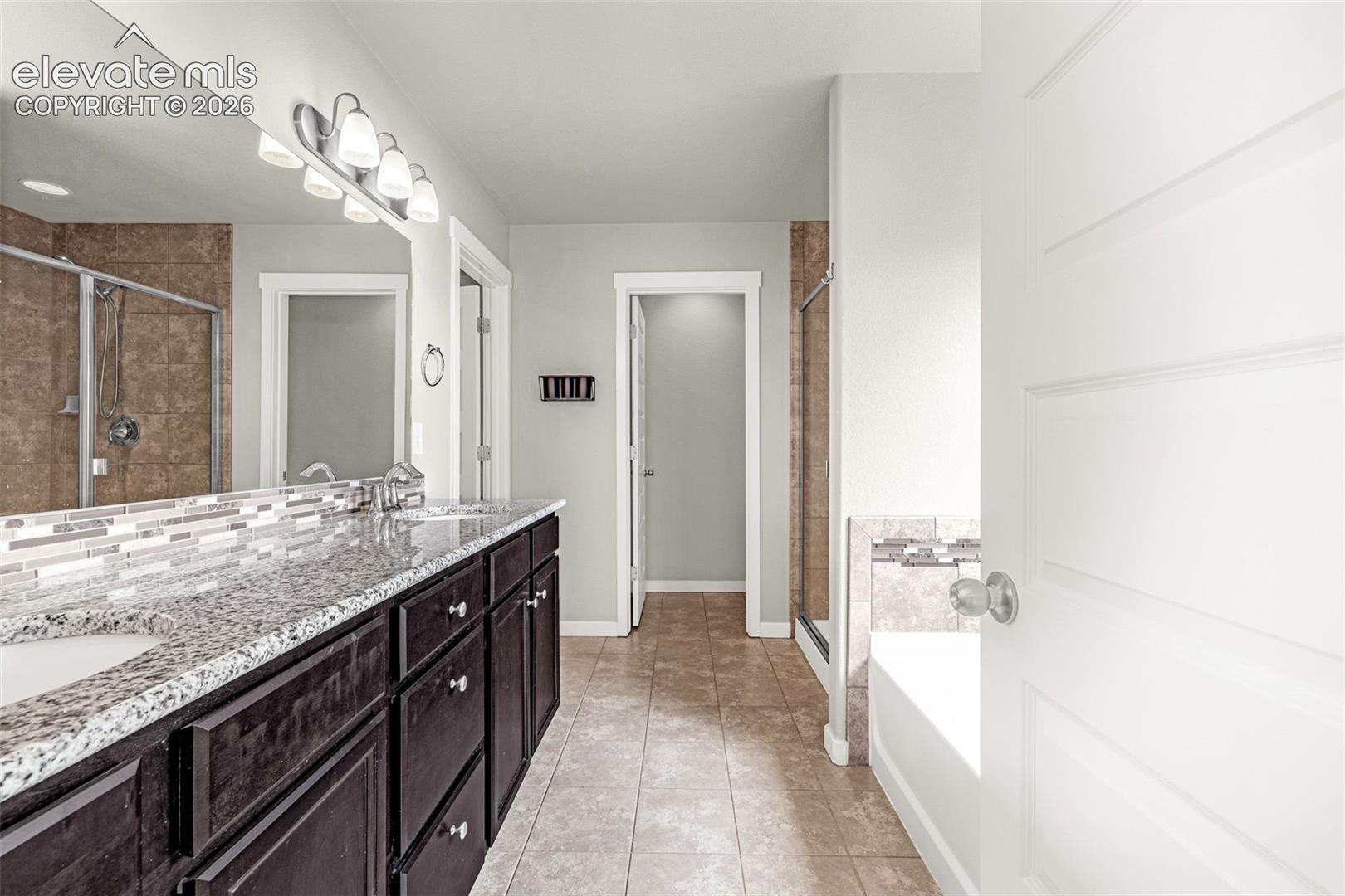 Dual vanity with granite countertop and dark wood-finish cabinetry