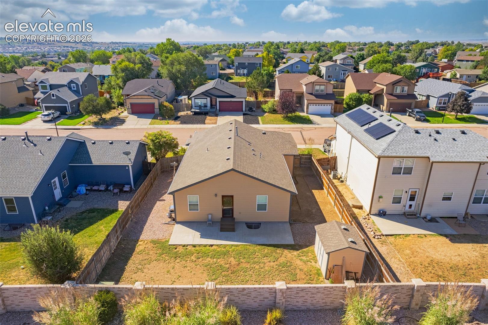 Rear exterior with a concrete patio, wood fence, and an auxiliary storage shed