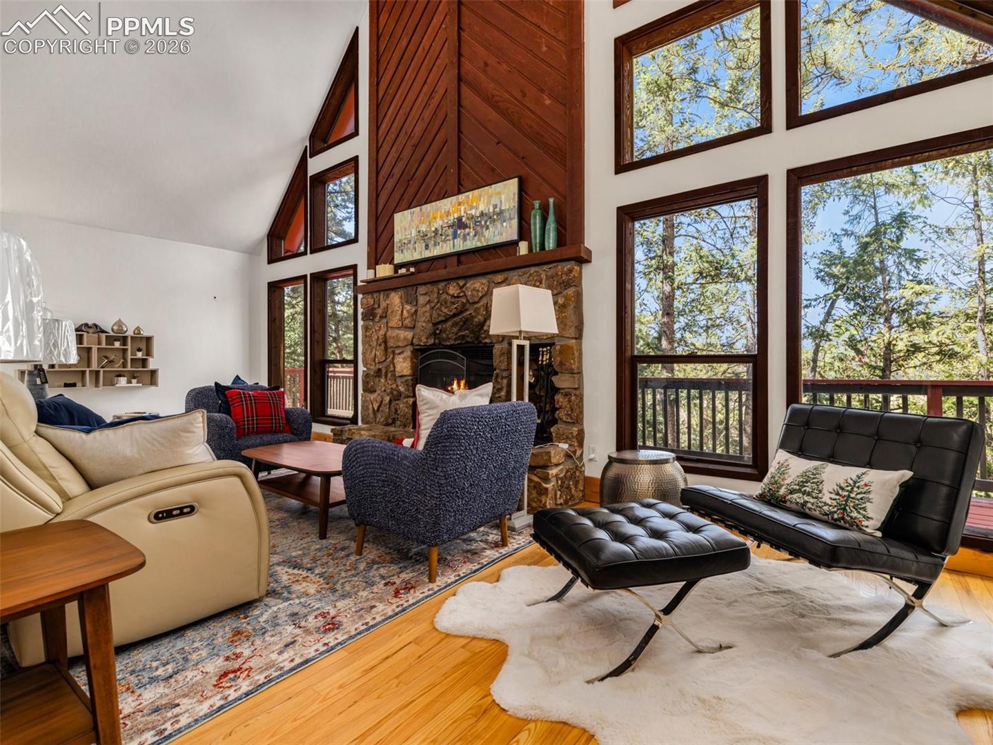 Living area featuring hardwood / wood-style flooring, a stone fireplace, and lofted ceiling
