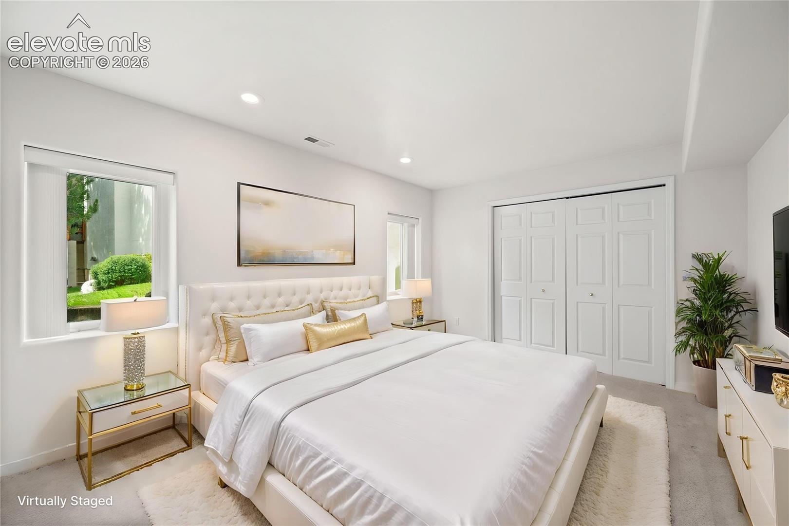 Bedroom featuring neutral walls, recessed lighting, dual windows, and bi-fold closet doors