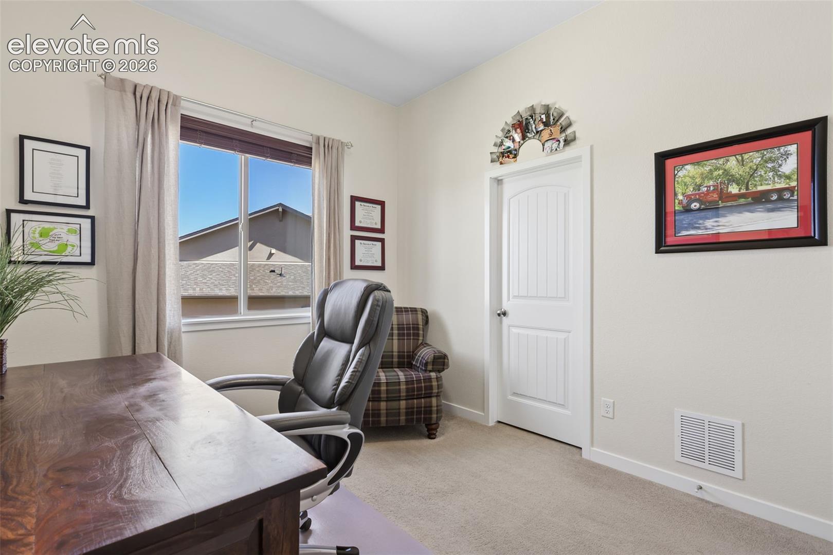 Bright room with carpet flooring, a paneled door, and a large window