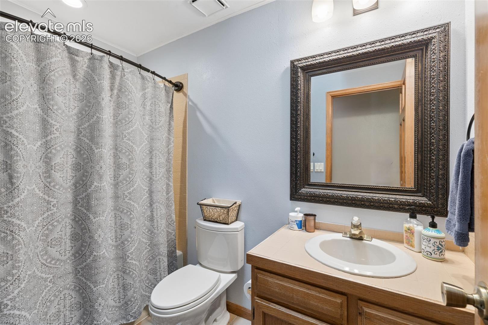 Bathroom featuring a wood-finish vanity cabinet, integrated sink with metallic faucet, and a large decorative wall mirror
