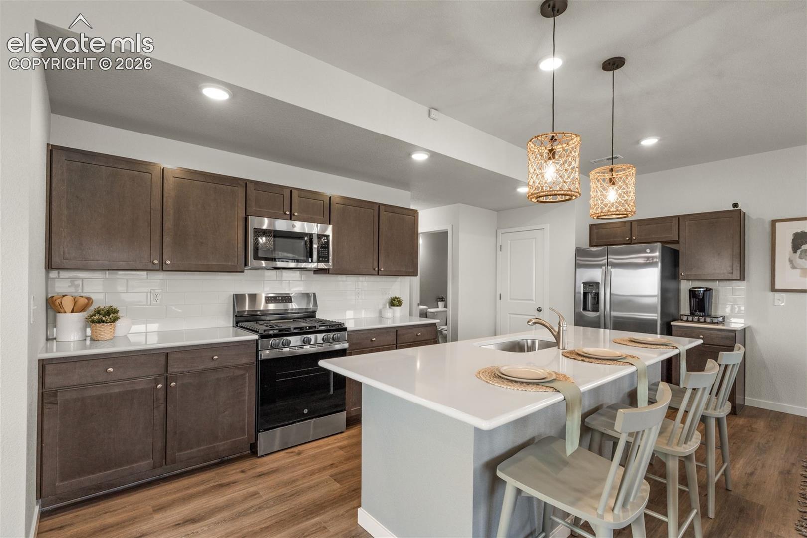 Kitchen featuring a center island, stainless steel appliances, wood-finish flooring, recessed lighting, and white subway tile backsplash