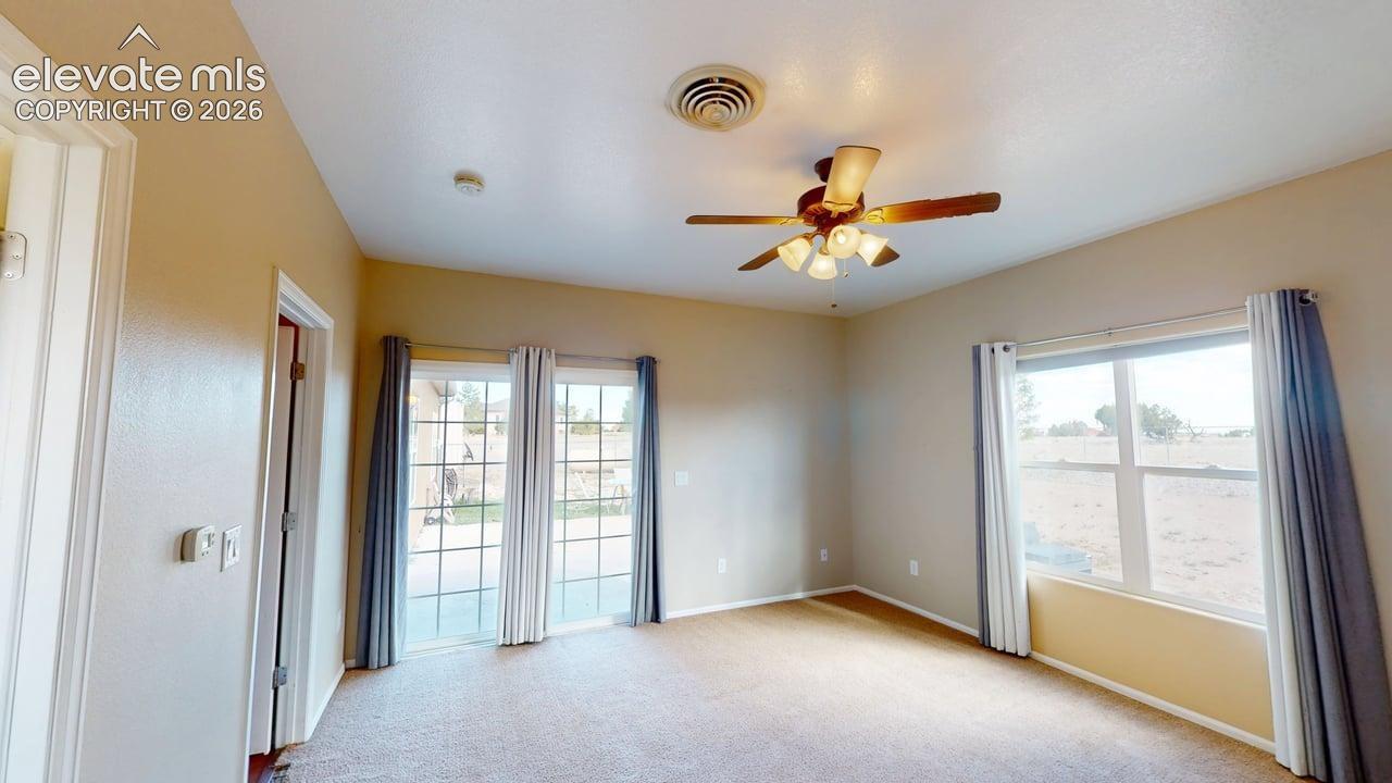 Neutral tone wall paint, carpet flooring, a ceiling fan with integrated lighting, and a window with vertical blinds