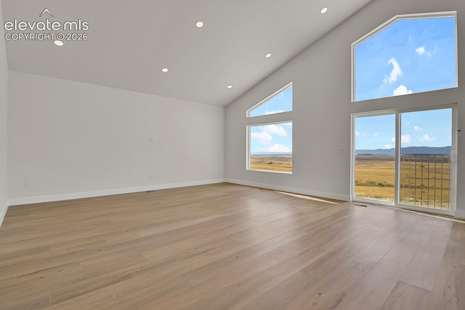 Vaulted ceilings featuring recessed lighting, wood-finish flooring, and expansive windows with mountain and terrain scenery
