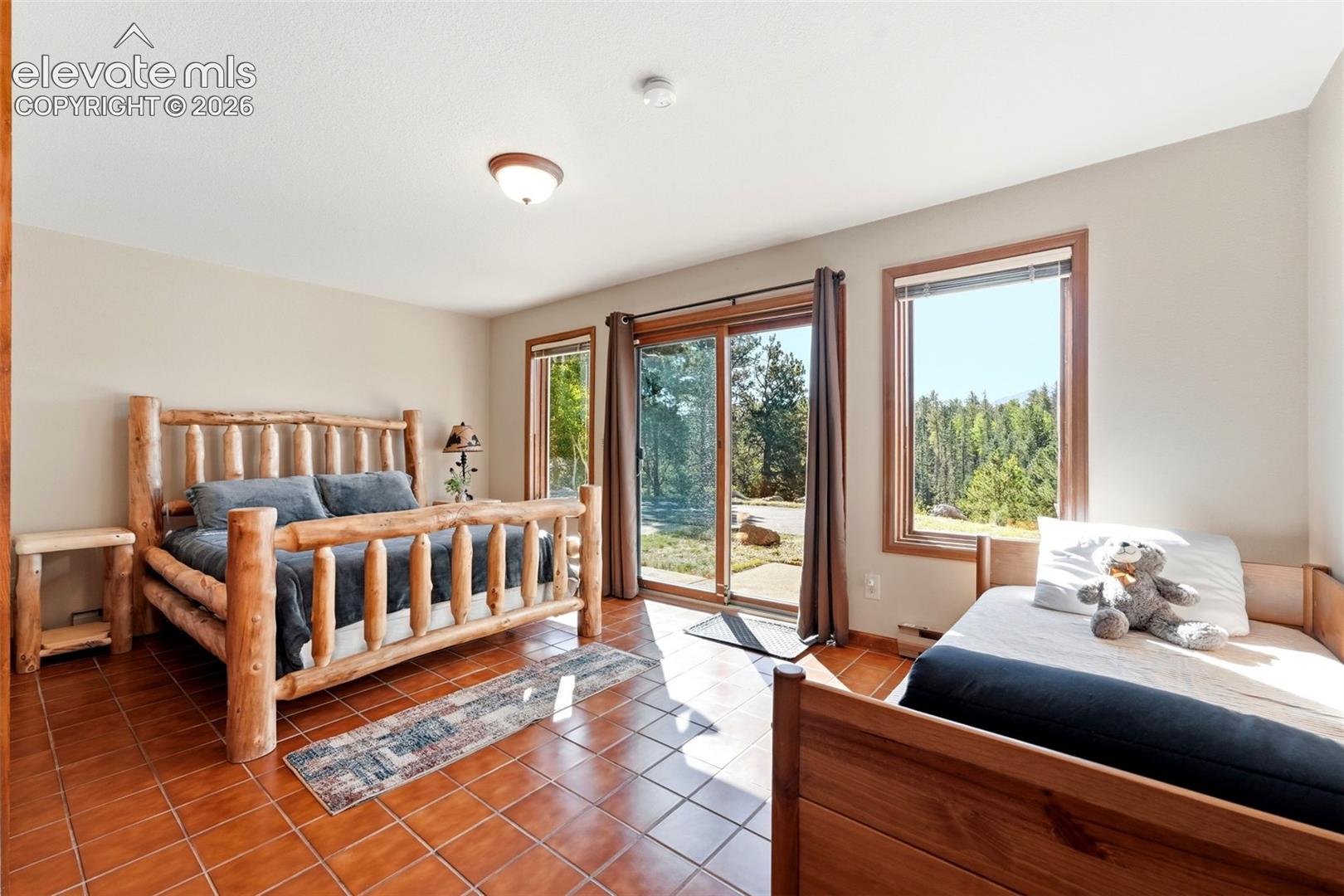 Terracotta-style tile flooring, sliding glass door with outdoor access, large casement window, and neutral wall color