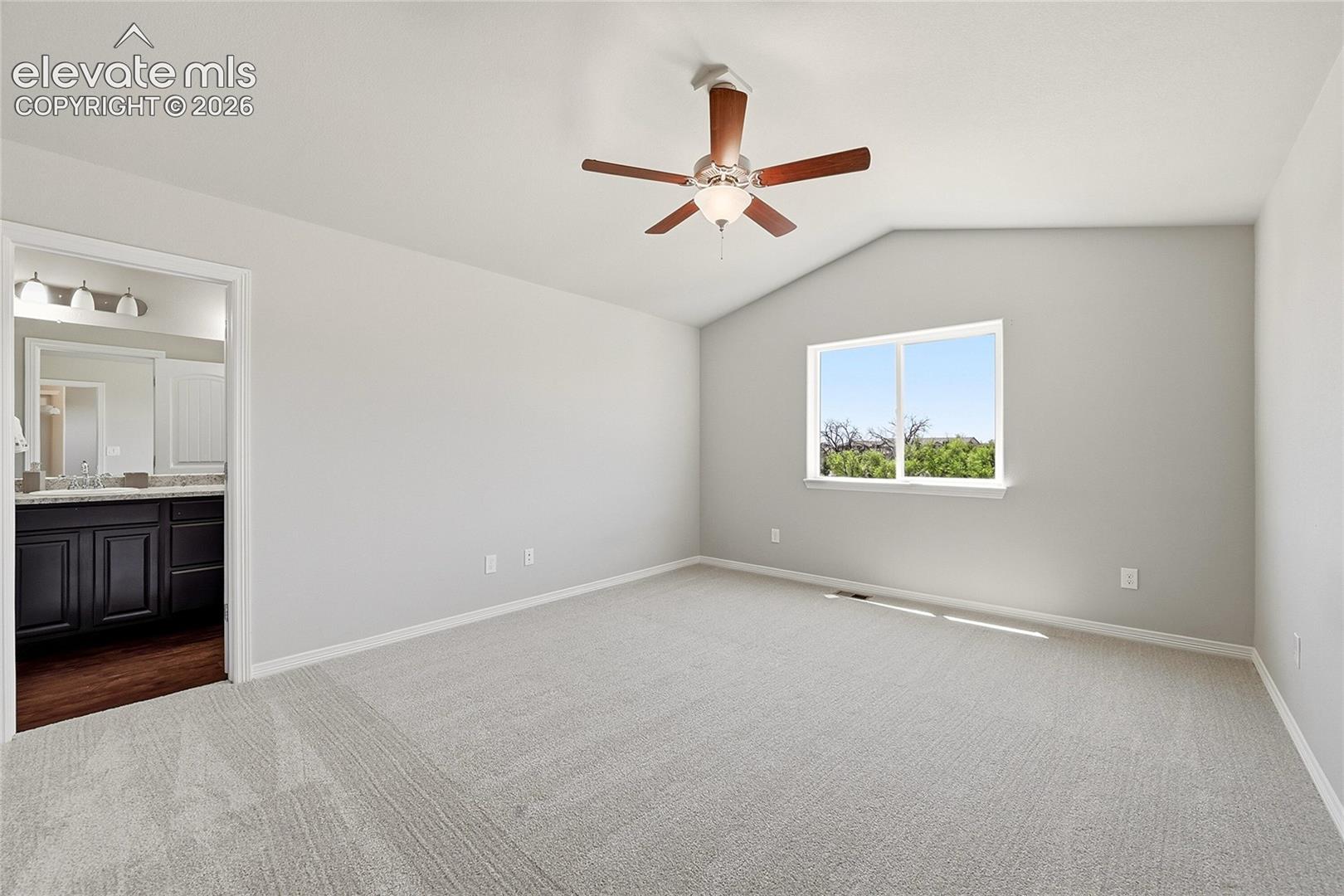 Spacious room featuring vaulted ceilings, light gray wall tones, and neutral carpeting