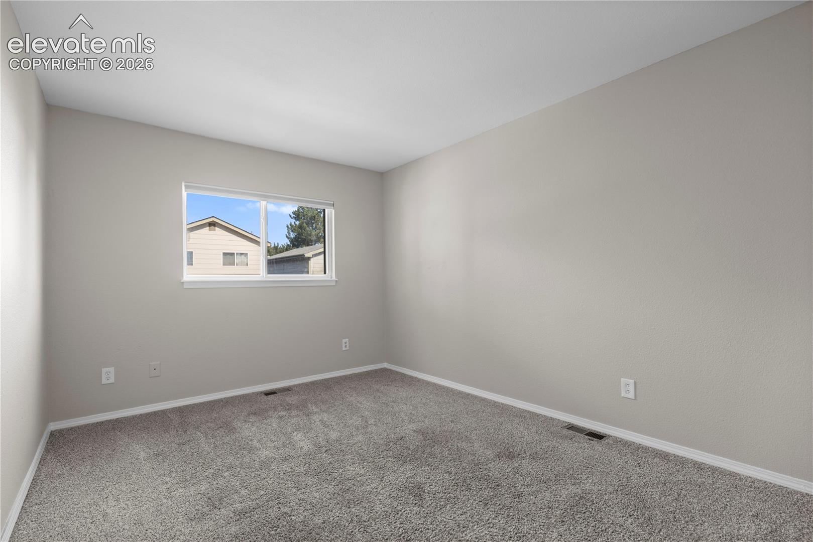 Neutral-toned interior space featuring light-colored wall paint, carpeted flooring, and a sliding window