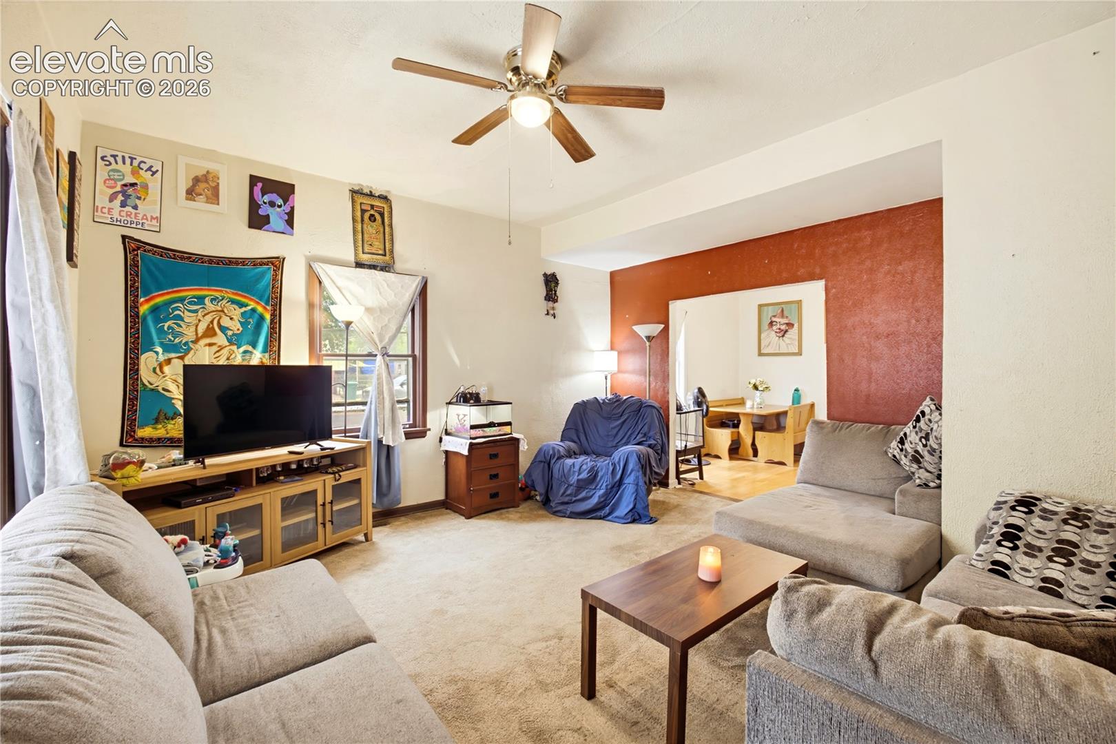 Recessed entryway leading to an interior space with a ceiling fan, carpeted flooring, and a window