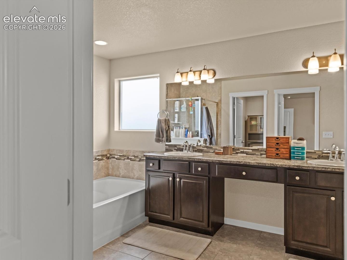 Dual vanity with rich wood-finish cabinetry, integrated sinks, and polished chrome fixtures