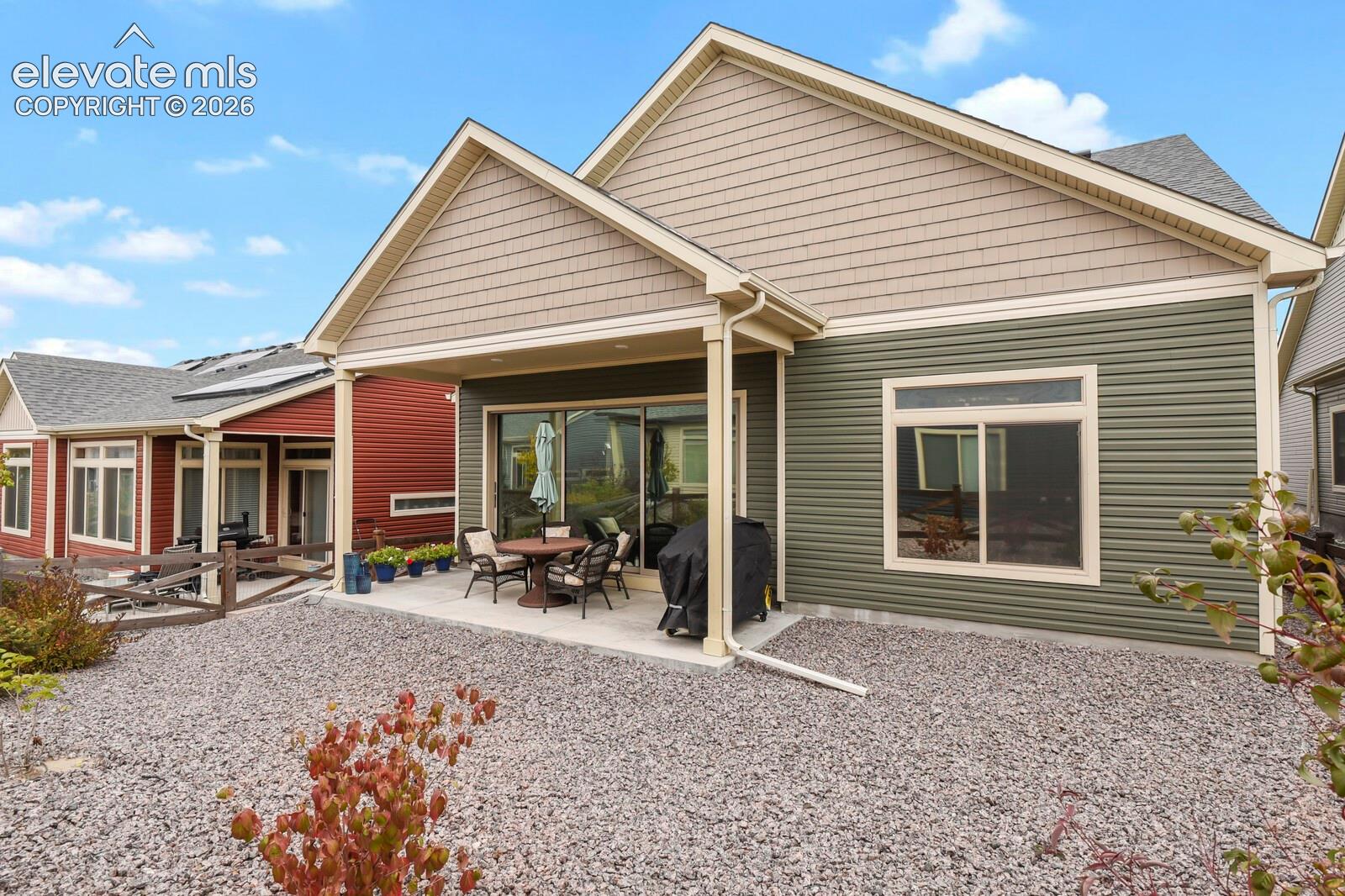 Exterior featuring horizontal and shingle-style siding, covered concrete patio, and gravel landscaping