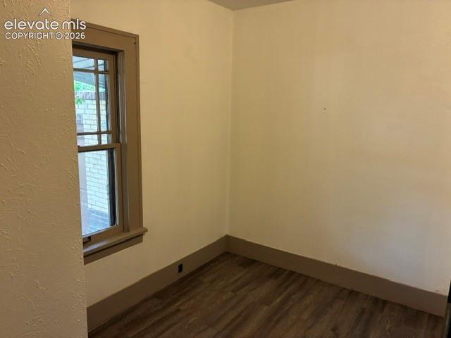 Room featuring wood-finish flooring, a double-hung window with muntins, and neutral-toned walls