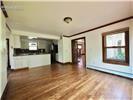 Open-concept interior featuring wood-finish flooring, crown molding, and wooden window trim