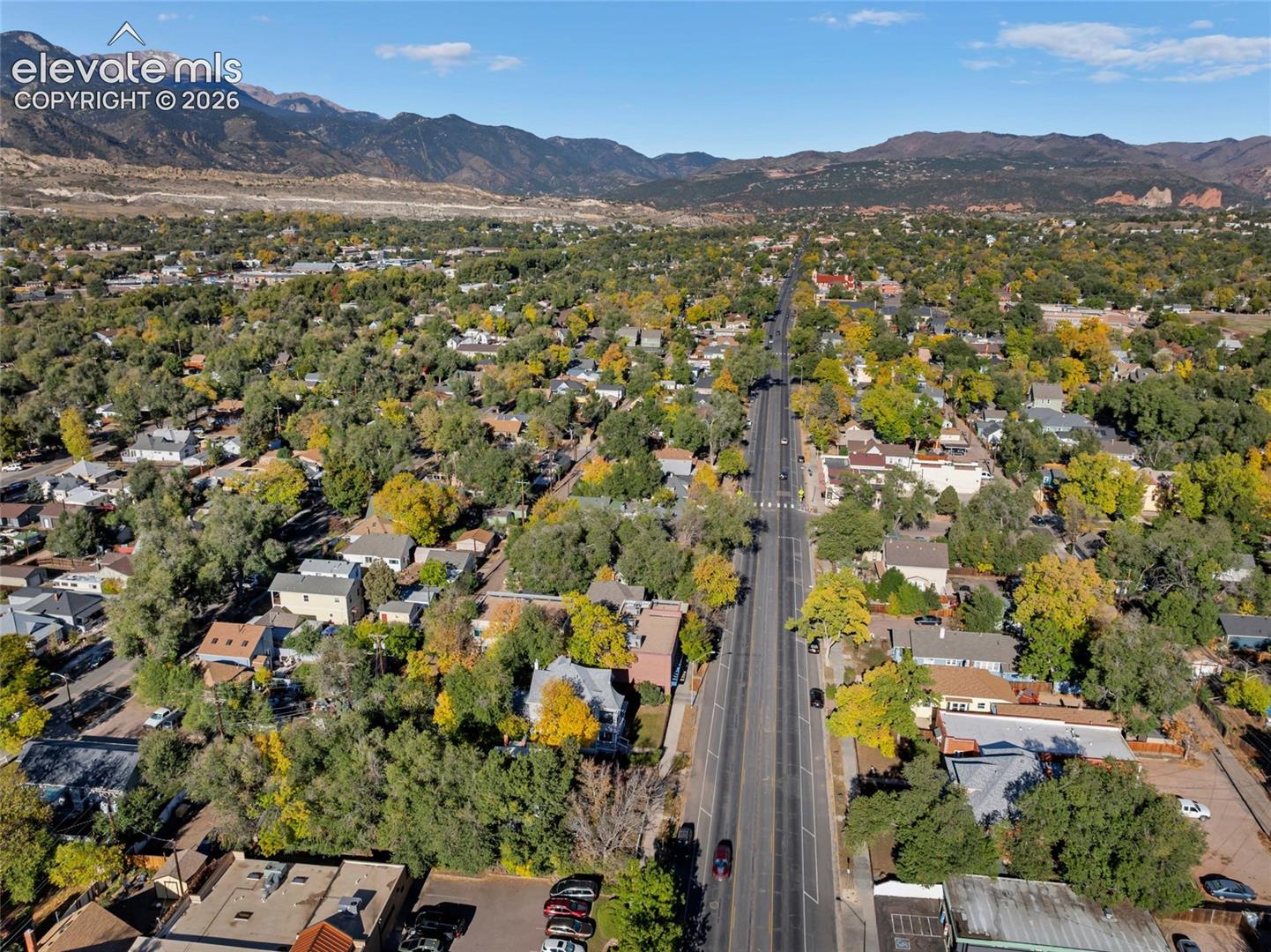 Aerial perspective featuring a neighborhood with mature trees and a prominent mountain range backdrop