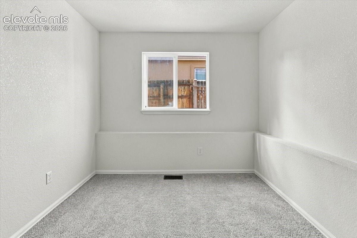 Room featuring neutral-toned wall-to-wall carpeting, textured wall finishes, and a sliding window