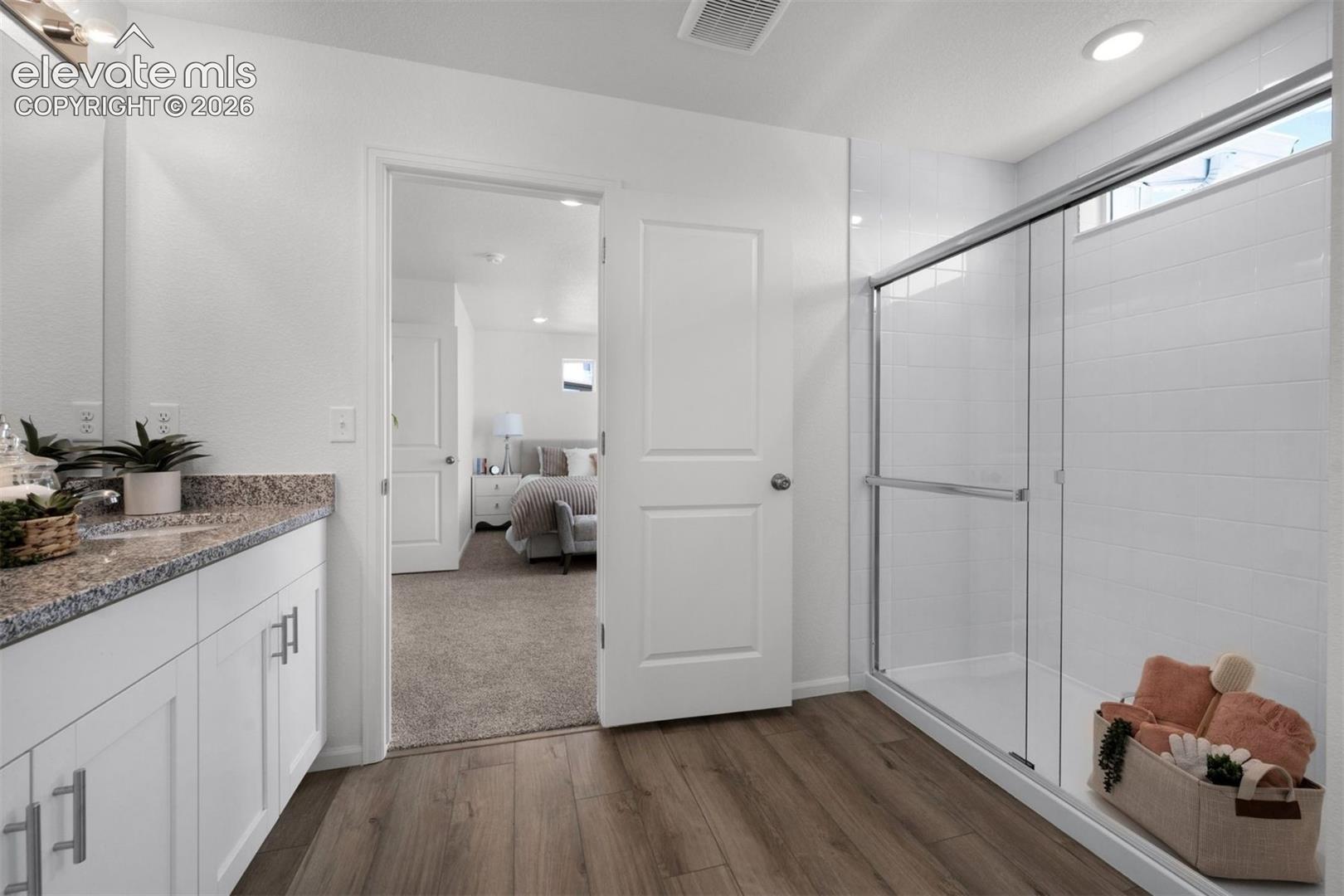 Wood-finish flooring with a white vanity featuring a speckled countertop
*photos of a model home*