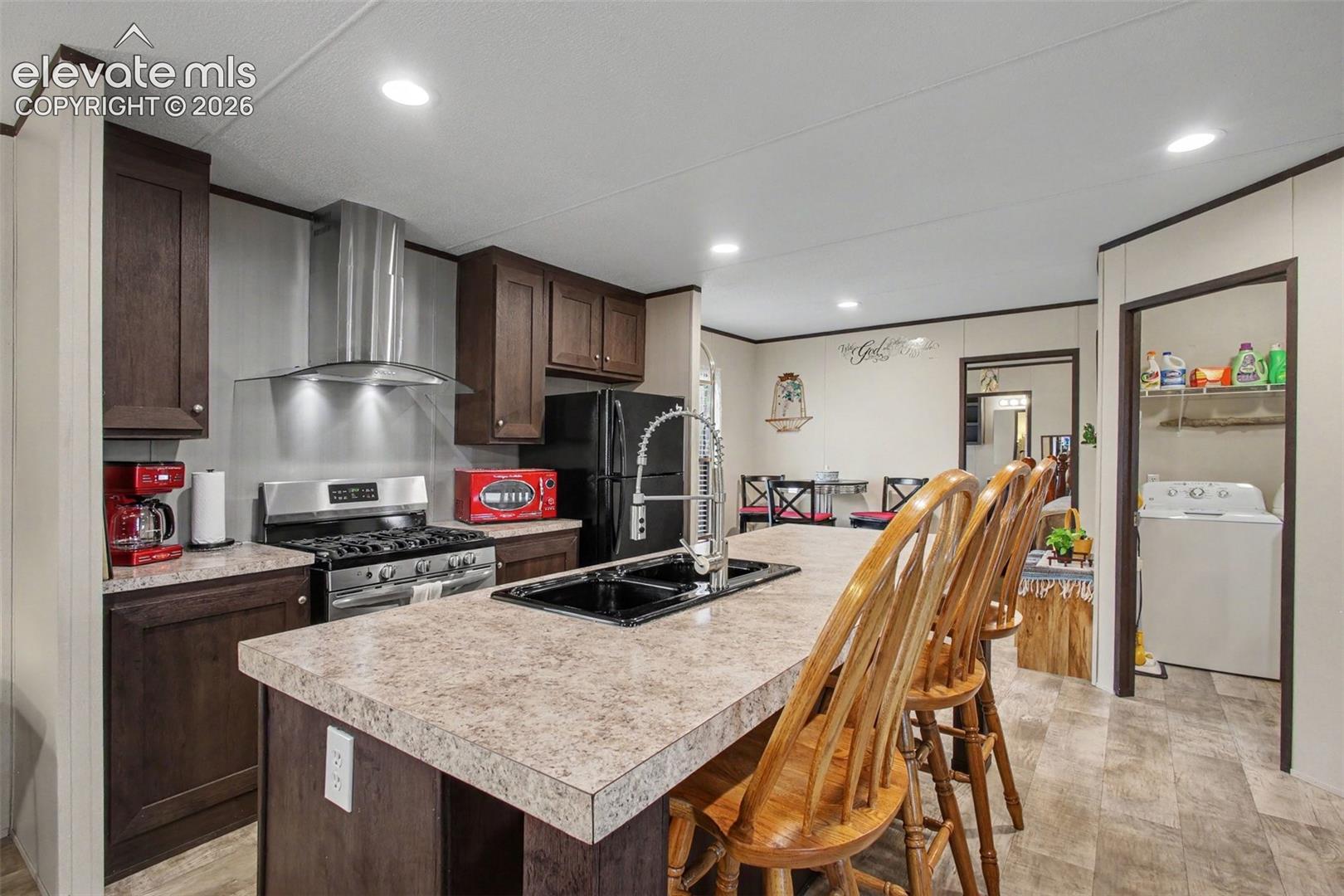 2nd Home: Modern kitchen featuring  LVT flooring, a stylish vent hood, gas range, and a fresh, contemporary look perfect for everyday cooking and entertaining.
