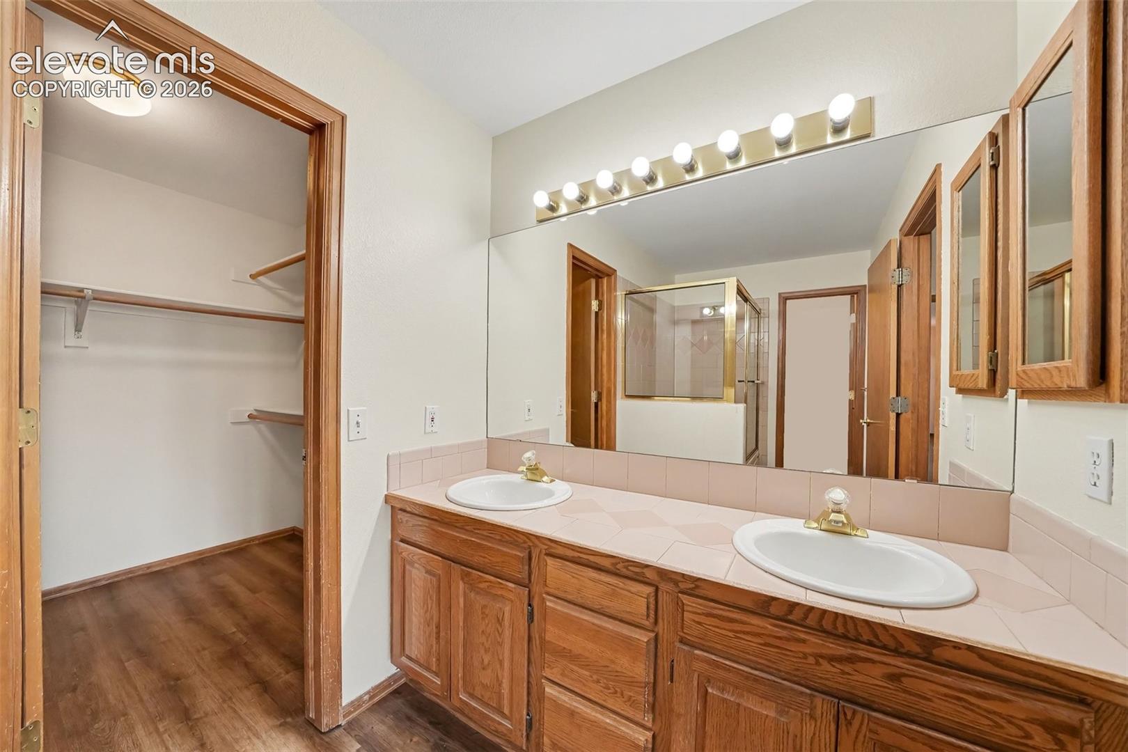 Double vanity with integrated sinks, expansive wall mirror, and overhead strip lighting